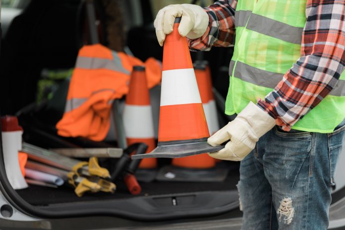 Man in a reflective vest and work gloves holding a bollard Man in a reflective vest and work gloves holding a bollard