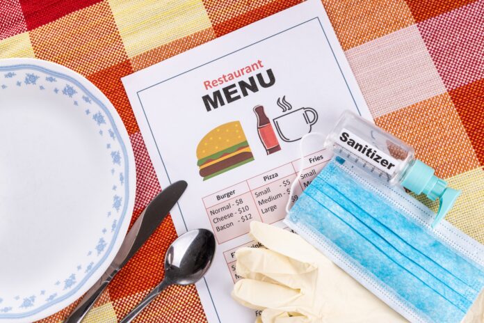 New normal lifestyle with sanitizer, face mask, gloves and disposable menu at restaurant New normal lifestyle with sanitizer, face mask, gloves and disposable menu at restaurant