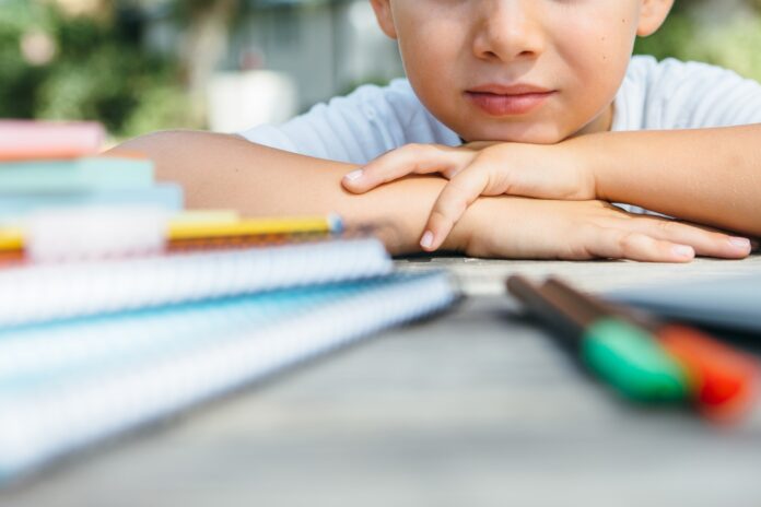 Crop child at table with school supplies Crop child at table with school supplies