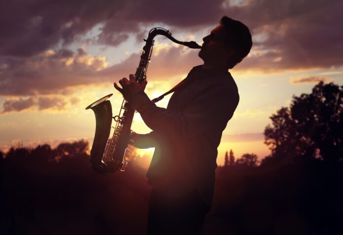 Saxophonist playing sax against sunset Saxophonist playing sax against sunset
