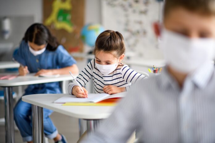 Children with face mask back at school after covid-19 quarantine and lockdown