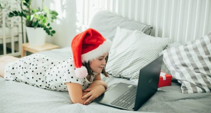 Girl in a hat of Santa Claus celebrates with family holiday of Christmas. COVID, social distancing