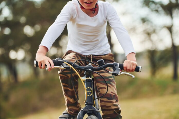 Young boy riding his bike outdoors in the forest at daytime Young boy riding his bike outdoors in the forest at daytime