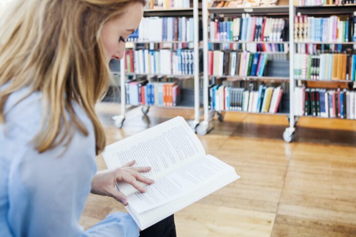 Young woman reading book in library Young woman reading book in library