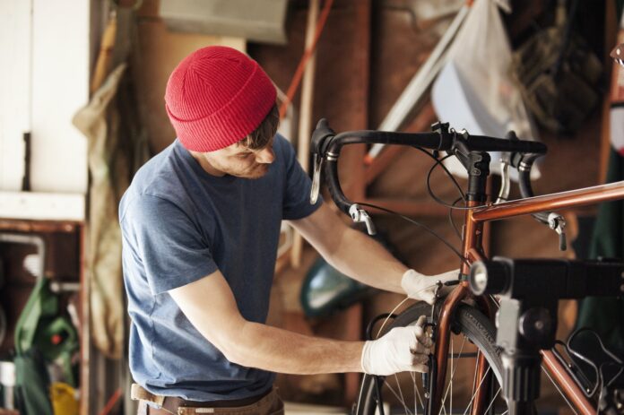 Mechanic Repairing Bicycle At Workshop