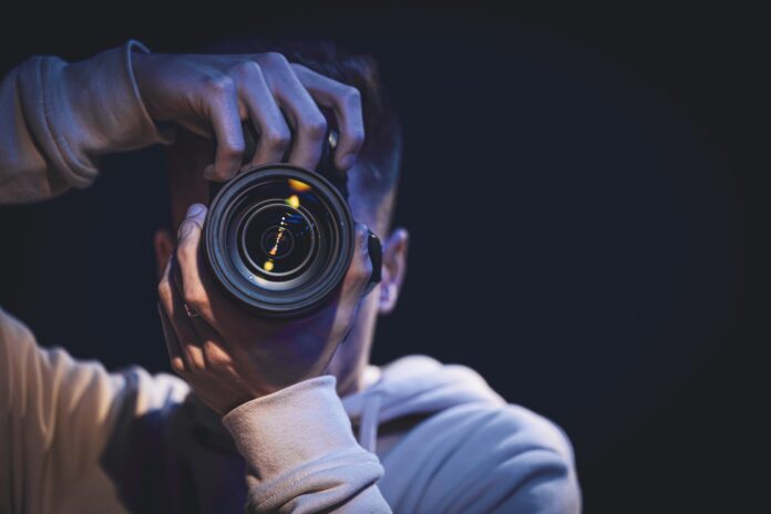 A man photographer with a camera takes a photo in the dark, copy space. A man photographer with a camera takes a photo in the dark, copy space.
