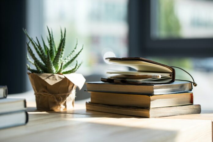 Close-up view of books, notebook with pencil and potted plant on wooden table Close-up view of books, notebook with pencil and potted plant on wooden table