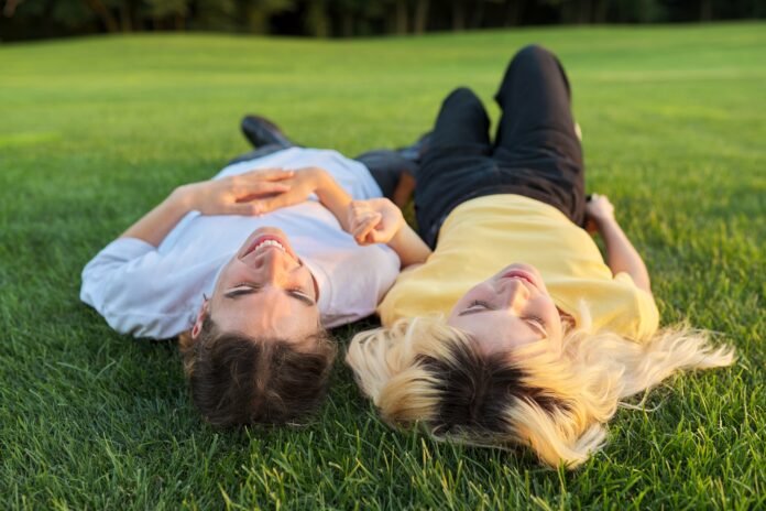 Happy couple of teenagers on green grass Happy couple of teenagers on green grass