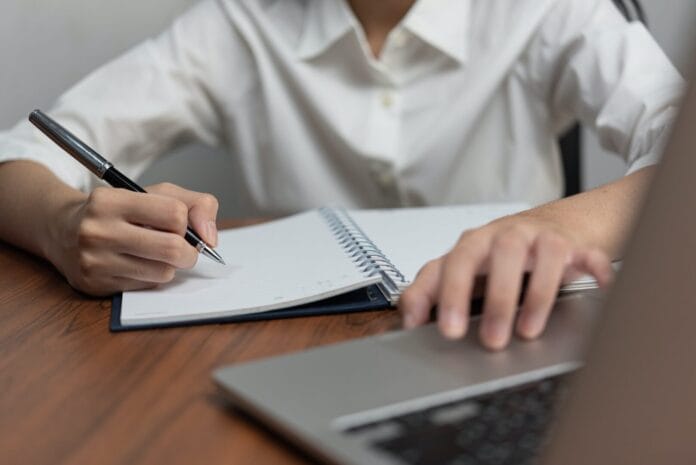 Businessperson reading and writing on book.